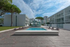 a building with a pool and lounge chairs in front of it at Jesolo Lido Village Immobiliare Pacella in Lido di Jesolo