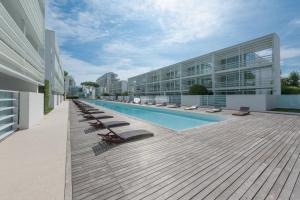 a large building with a swimming pool and lounge chairs at Jesolo Lido Village Immobiliare Pacella in Lido di Jesolo