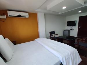 a hotel room with a white bed and a desk at Gangavaram Residency in Cuddapah