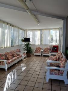 uma sala de estar com sofás e uma televisão e janelas em Hotel Marconi Miramare em Rimini