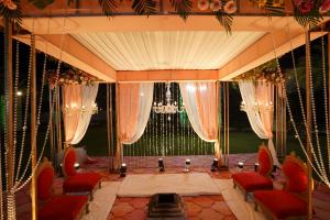 een kamer met rode stoelen en een podium met gordijnen bij Stardom Resort Jaipur in Jaipur