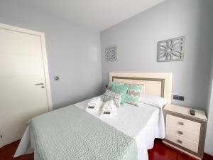 a bedroom with a bed with white sheets and blue pillows at Pension As Burgas Ii in Caldas de Reis