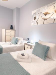a bedroom with two beds and a picture of flowers on the wall at Pension As Burgas Ii in Caldas de Reis