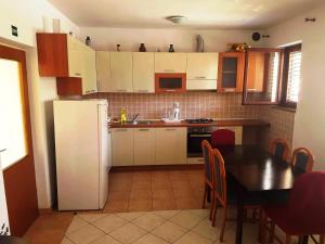 a kitchen with a table and a white refrigerator at Apartmani Henjak in Jezera