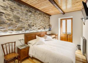 Casa Rural Francisco Mayo في إيسابا: غرفة نوم بسرير وجدار حجري