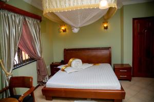- une chambre avec un lit doté de draps blancs et une fenêtre dans l'établissement Lush Garden Business Hotel, à Arusha