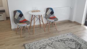 two chairs and a table in a room with a rug at Apartament Mario in Rădăuţi