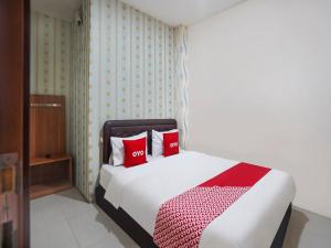 SUPER OYO 91049 D'lima Guest House Sub في Medokanayu: غرفة نوم مع سرير مع وسادتين حمراء