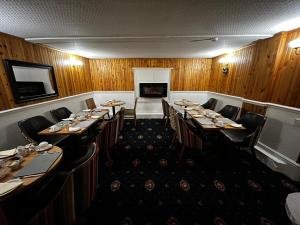 una sala da pranzo con tavoli, sedie e camino di DunMoore Guesthouse a Oban