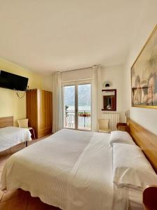 a bedroom with a large white bed and a window at Hotel Baitone - Nature Village in Malcesine