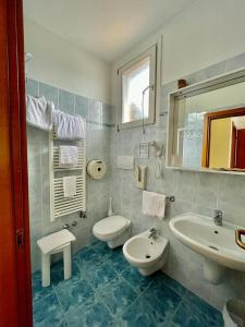 ein Badezimmer mit zwei Waschbecken, einem WC und einem Spiegel in der Unterkunft Hotel Baitone - Nature Village in Malcesine