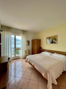 a bedroom with a bed and a desk and a window at Hotel Baitone - Nature Village in Malcesine