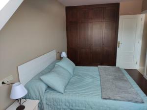 ein Schlafzimmer mit einem blauen Bett und einer Holztür in der Unterkunft Amaral Playa Jardín in Boiro