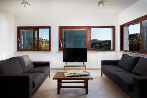 a living room with two couches and a flat screen tv at Homey Experience - White Villa Panorama in La Maddalena