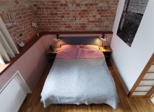 ein kleines Schlafzimmer mit einem Bett in einer Ziegelwand in der Unterkunft Zur alten Scheune in Balingen