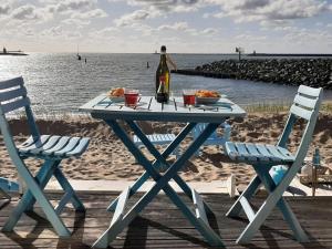 una mesa de picnic con una botella de vino y 2 sillas en Beachhouse direct aan zee en IJmuiden