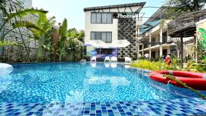 una piscina con sillas y sombrillas junto a un edificio en PHOENIX MINH CHÂU HOTEL en Quang Ninh