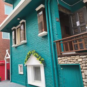 a blue house with a door and a balcony at Batwo Stay - For foreigners only in Seoul