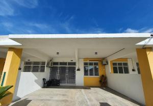 une maison blanche aux murs jaunes et blancs dans l'établissement Licuala Homestay Bukit Keluang, à Kampung Raja