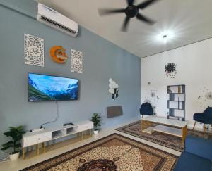 uma sala de estar com uma televisão de ecrã plano na parede em Licuala Homestay Bukit Keluang em Kampung Raja