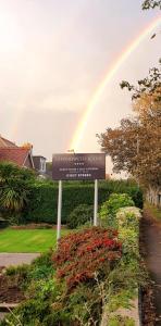 a rainbow in the sky over a sign with a street at Chynoweth Lodge in Newquay