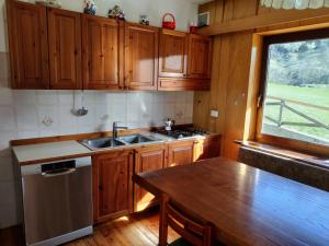 eine Küche mit Holzschränken, einem Tisch und einem Fenster in der Unterkunft Varabeta in Forni di Sopra