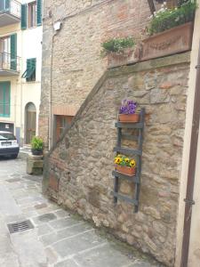 Una pared de piedra con un estante con flores. en Helga's House- Una Finestra sul Borgo, en Ambra
