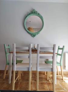 a dining room table with chairs and a mirror at O'Eirado Playa de Quenxe in Corcubión