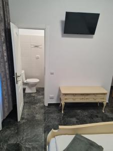 a bathroom with a toilet and a table and a tv at Casa Sofia in Anina