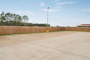 una pista de tenis vacía con una valla de madera en Super 8 by Wyndham Gulfport Biloxi Airport en Gulfport