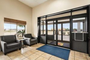 eine Lobby mit 2 Stühlen, einem TV und Fenstern in der Unterkunft Super 8 by Wyndham Gulfport Biloxi Airport in Gulfport