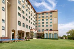 a large building with a lawn in front of it at Ramada by Wyndham Jaipur Jaisinghpura in Jaipur