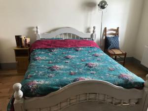 a bed with a green quilt with flowers on it at An Bothán-Cosy Cottage in the Cooley Mountains in Dundalk