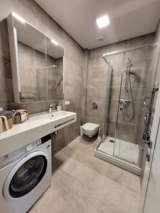 a bathroom with a washing machine and a shower at New Apartment,free parking in the Center in Klaipėda