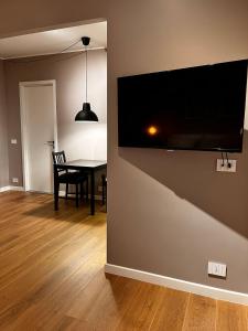 a dining room with a table and a flat screen tv on a wall at DeGasperi Studio Apartment in Trani