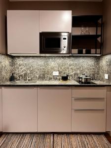 a kitchen with white cabinets and a microwave at DeGasperi Studio Apartment in Trani