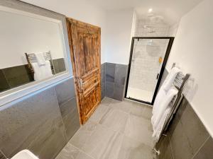 a bathroom with a shower with a wooden door at Ravenscraig Guest House in Aviemore