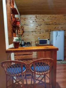 a kitchen with a counter with two chairs and a refrigerator at Cabana Recanto do Physalis in Rio Rufino