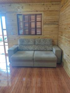 a couch sitting in a room with wooden walls at Cabana Recanto do Physalis in Rio Rufino