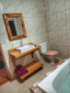 a bathroom with a sink and a toilet and a mirror at Cabana Recanto do Physalis in Rio Rufino