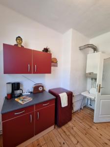 cocina con armarios rojos y encimera en Harztour 3 Ferienwohnung, en Quedlinburg