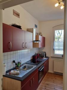 una cocina con armarios rojos y fregadero en Harztour 3 Ferienwohnung, en Quedlinburg