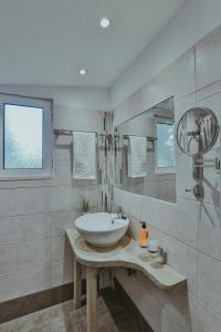 La salle de bains blanche est pourvue d'un lavabo et d'un miroir. dans l'établissement Sunny Garden Aparthotel, à Ancient Epidavros
