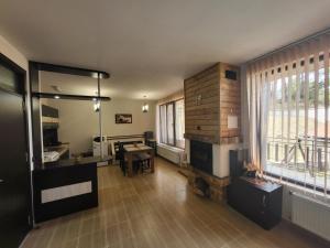 a living room with a fireplace and a table at Ваканционна къща ,,Родопски уют " in Dospat