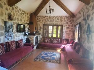 a living room with purple couches and a tv at Joli Chalet dans une ferme Pour familles exclusivement près ifrane in Azrou
