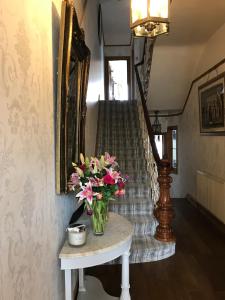 a vase of flowers on a table next to a staircase at Wisteria house in Plymouth
