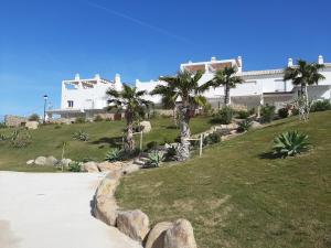 a large white building with palm trees on a hill at Casa adosada Rompeolas-Atlanterra in Zahara de los Atunes