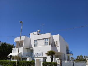 a white building with a palm tree in front of it at Le Dune camere in Otranto