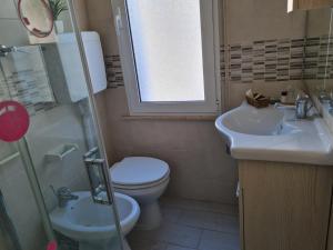 a bathroom with a toilet and a sink and a window at Hotel Marconi Miramare in Rimini