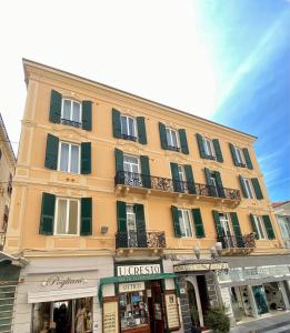 a large yellow building with green shutters on a street at Hotel Eletto in Sanremo